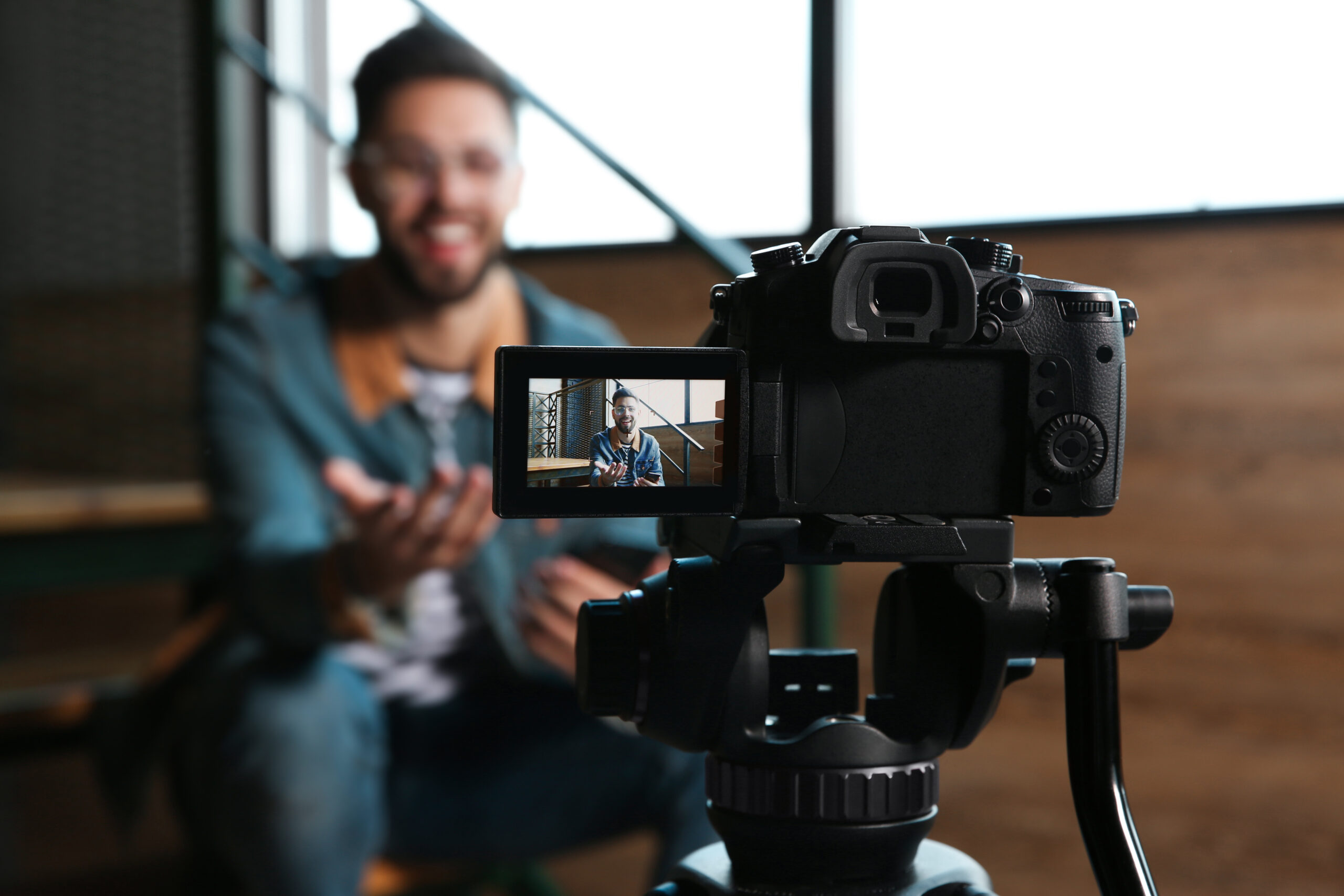 Young blogger recording video indoors, focus on camera screen