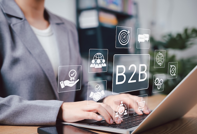 B2B Marketing and Business Collaboration Strategy Concept. Businesswoman using laptop with B2B marketing icons, symbolizing business to business communication, collaboration, trade, and strategy.