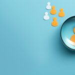 Yellow human icon in magnifying glass among white icons on blue background symbolizing customer focus hr recruitment and crm management banner with space for copy and orange accents