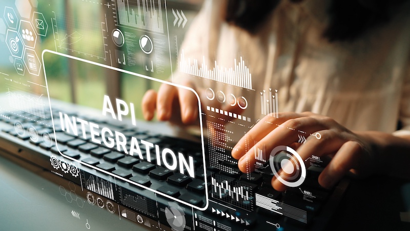 Hands typing on keyboard with digital graphics showing data and API integration concept in modern office environment. Asymptotic smart data analytic