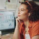 Business, thinking and woman in office, ideas and contemplation with sound, listening to music and audio. Person, creative agency and entrepreneur with earphones, podcast and calm with daydreaming