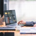 Businesswoman accountant using a calculator, graphs, and charts to analyze market data, balance sheets,accounts,and net profits in order to plan new sales strategies.