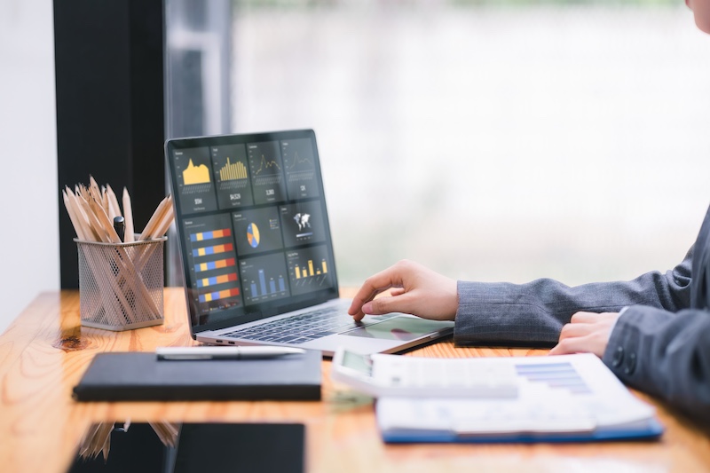 Businesswoman accountant using a calculator, graphs, and charts to analyze market data, balance sheets,accounts,and net profits in order to plan new sales strategies.
