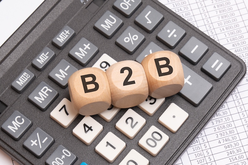 B2B letters on wooden cubes placed on calculator and financial spreadsheet