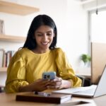 Smiling Indian woman using her smartphone in office