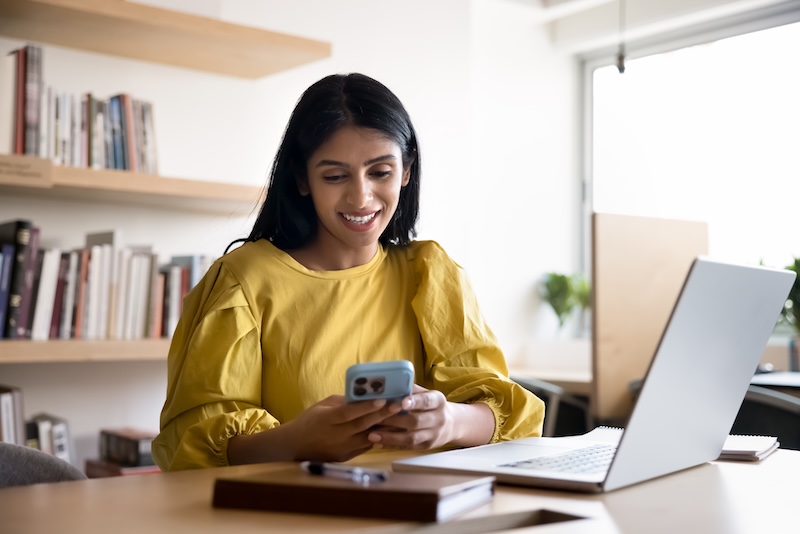 Smiling Indian woman using her smartphone in office