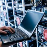 IT specialist working on computer in bitcoin and crypto currency mining farm.