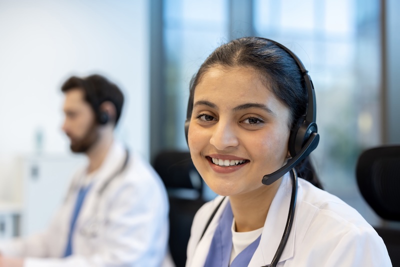 A smiling healthcare professional wearing a headset ready to assist and provide patient support.