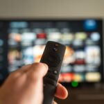 Vibe.co A person holds a remote in front of a vibrant TV screen, ready to browse and enjoy shows
