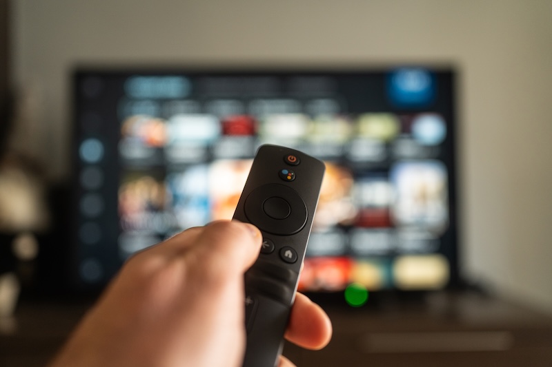 Vibe.co A person holds a remote in front of a vibrant TV screen, ready to browse and enjoy shows