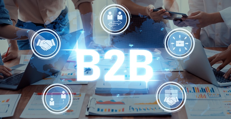 Demandbase #COSeries Collaborative Business Partnership in B2B Environment with Laptops, Documents, and Digital Icons Representing Networking, Communication, and Teamwork Trope