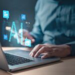 Demandbase AI A man is using a laptop with a blue screen chat bubble that has a blue word that says AI.