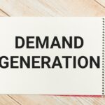 Vereigen Media Launches Revenue-First Demand Generation Programs Phrase demand generation written on note book with a marker pen and eye glasses.
