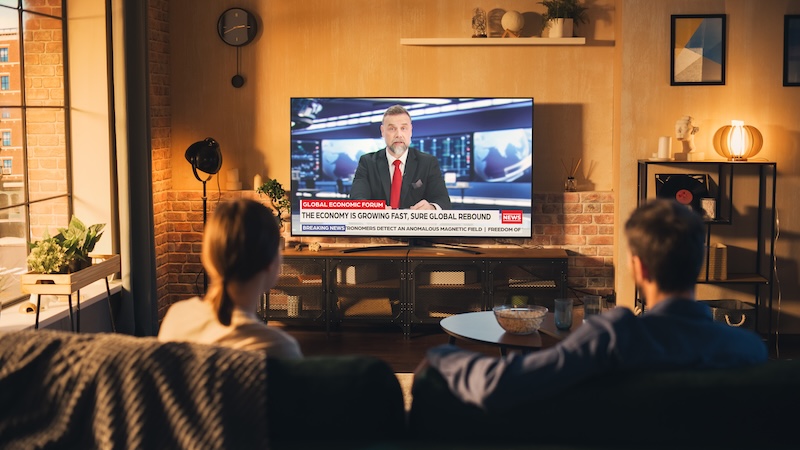 Wurl: Data Backs Advertising on Streaming News Channels Beautiful Couple Watching News On Television Set in Cozy Loft Apartment. Young Man and Woman are Catching Up With the Latest Events and Enjoying the Weekend in Tastefully Furnished Flat.