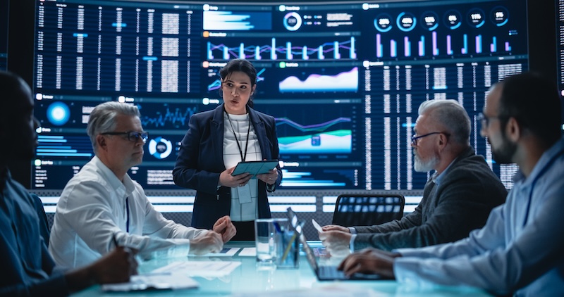 insightsoftware’s Lusha Success Multiethnic Chief Financial Officer Holding a Meeting with a Group of Fintech Investors. Diverse Team of Managers, Analysts and Board Members Having a Meeting in Front of Big Digital Screen
